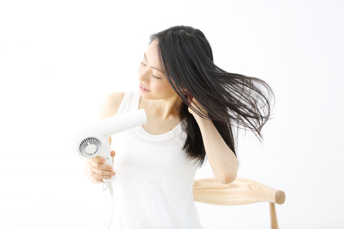 髪をドライヤーで乾かす女性